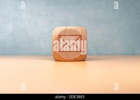 Wooden cube with a letter on top, symbolizing communication, messages, correspondence, or postal concepts in a clean, minimalistic style for business Stock Photo