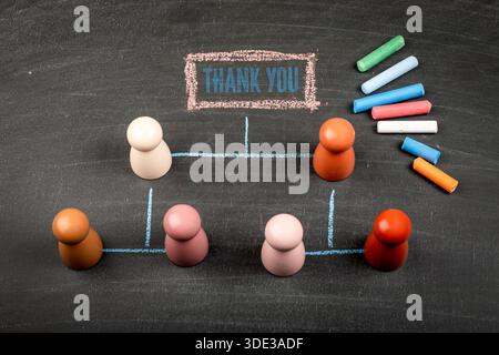 Thank You Concept Shown With Wooden Figures, Chalk Lines And Message On Blackboard Stock Photo