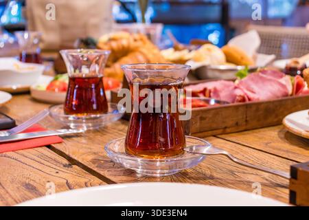 Glass of traditional Turkish tea served on a wooden table during breakfast in a cafe or restaurant. Stock Photo