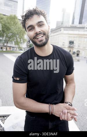 Cool easygoing man being approachable and friendly rubbing hands together with attentive ease in inner city of Frankfurt am Main in Germany, being chi Stock Photo