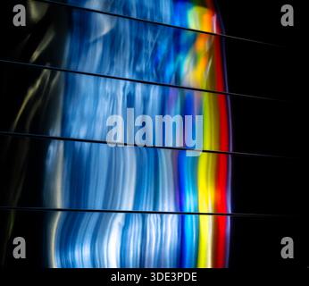 a colorful, abstract light display. The image features wavy, blue, white, and gray light patterns on the left, with a vibrant, multicolored rainbow-li Stock Photo