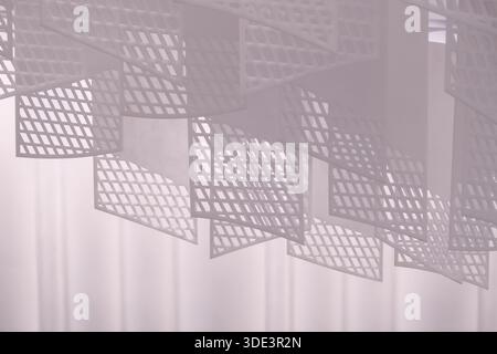 a series of geometric, lattice-patterned paper lanterns hanging from the ceiling. The lanterns are rectangular with a grid-like design, casting intric Stock Photo