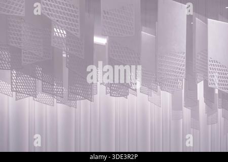 a series of geometric, lattice-patterned paper lanterns hanging from the ceiling. The lanterns are rectangular with a grid-like design, casting intric Stock Photo