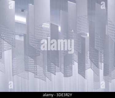 a series of geometric, lattice-patterned paper lanterns hanging from the ceiling. The lanterns are rectangular with a grid-like design, casting intric Stock Photo