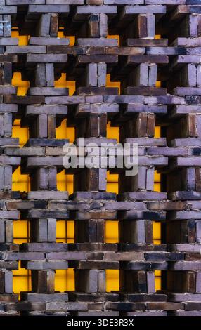 a textured brick wall featuring a complex, three-dimensional pattern. The bricks are arranged in a staggered, interlocking design, creating a series o Stock Photo