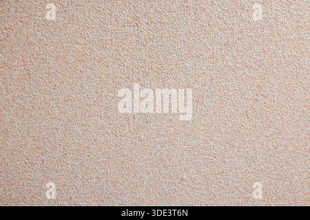 A textured beige wall background with a subtle grainy appearance. The surface is smooth and uniform, suitable for various design applications. Stock Photo