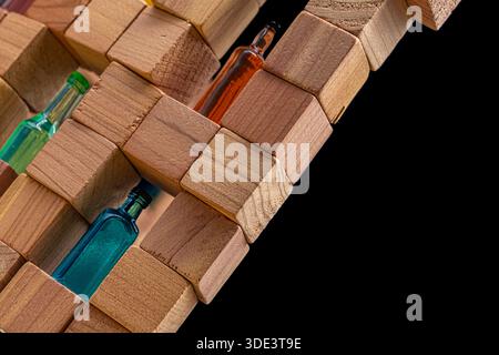 A wall made of wooden cubes with various miniature bottles of alcohol without labels on dark bacground Stock Photo