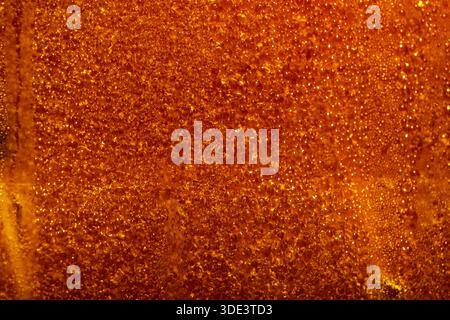 a vibrant golden surface covered in numerous small water droplets. The red background is slightly textured, creating a subtle gradient effect. Stock Photo