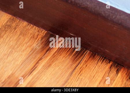 Rotting laminate floor with wooden baseboards in a damp room. Damaged decayed material Stock Photo