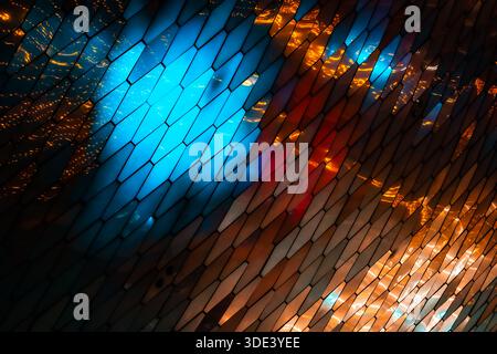 abstract, geometric wall made of hexagonal, glass-like tiles. The tiles reflect colorful lights creating a vibrant, shimmering effect. The overall tex Stock Photo