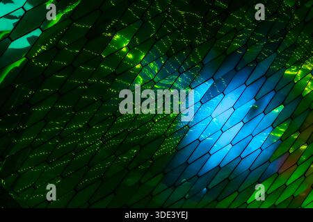 abstract, geometric wall made of hexagonal, glass-like tiles. The tiles reflect colorful lights creating a vibrant, shimmering effect. The overall tex Stock Photo