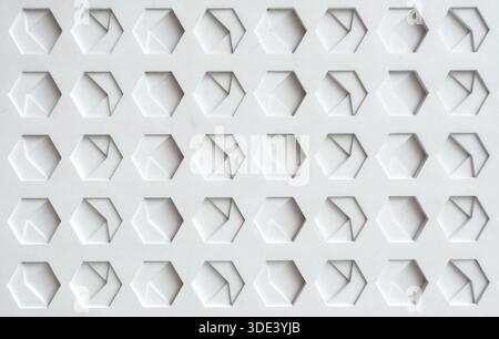 a white, textured surface featuring a grid of hexagonal indentations. Each hexagon has a three-dimensional, geometric design with internal triangular Stock Photo