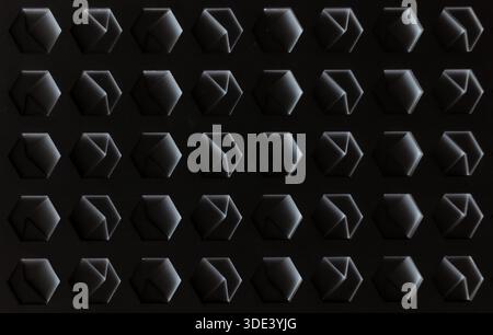 a white, textured surface featuring a grid of hexagonal indentations. Each hexagon has a three-dimensional, geometric design with internal triangular Stock Photo