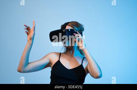 Woman interacting with virtual reality environment using hand movements, futuristic VR technology and immersive experience concept Stock Photo