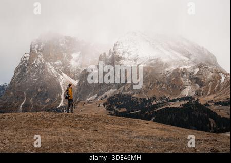 Hiker standing on alpine meadow with snowy Dolomites mountains, Italy Stock Photo