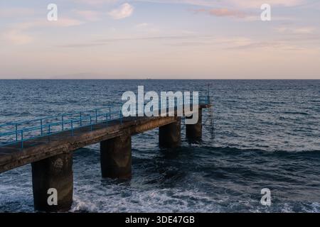 Concrete pier with blue railings over the ocean at sunset in Madeira Stock Photo