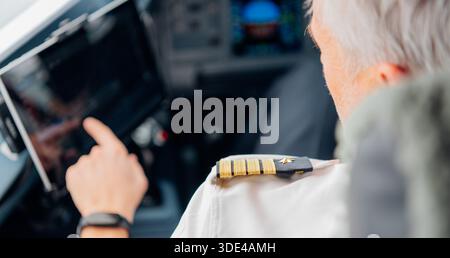 Senior male pilot using digital touchscreen in airplane cockpit Stock Photo