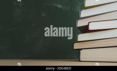 Stack of Hardcover Books on Desk with Green Blackboard Copy space. 3d rendering Stock Photo