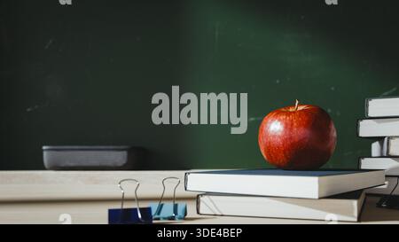 Red Apple on Stack of Books with School Blackboard Background. 3d rendering Stock Photo