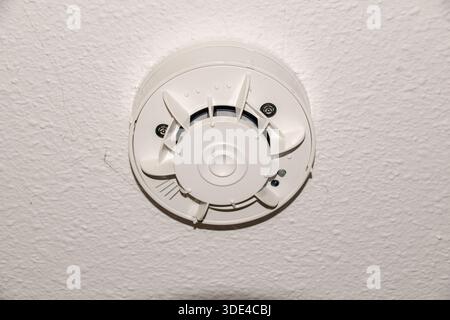 Ceiling-mounted home smoke detectors are essential safety devices that work best when installed near the center of the room. Stock Photo