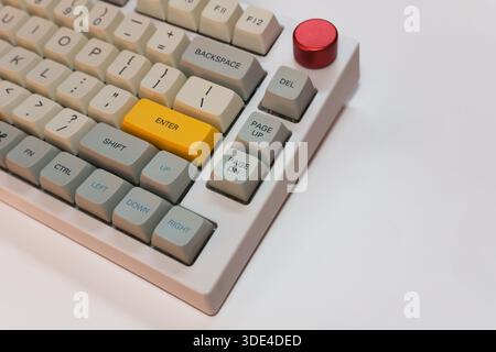 White mechanical keyboard with bright Enter key on white background, minimalism, keyboard buttons. A keyboard with a yellow key. High quality Stock Photo