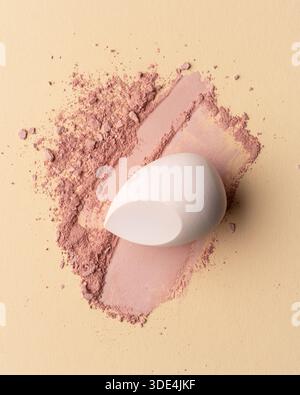 Makeup sponge on soft powder texture with visible application marks. Minimal beauty still life emphasizing tactility, softness, and natural imperfecti Stock Photo