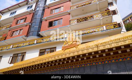 A modern building featuring traditional Buddhist decorations and balconies, with a clean, linear facade structure. Stock Photo