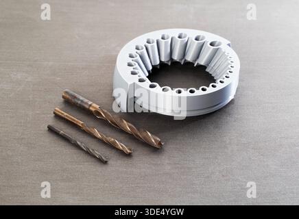 A gray round tool with holes of different sizes for sharpening drills through a grinder, close-up, gray background Stock Photo