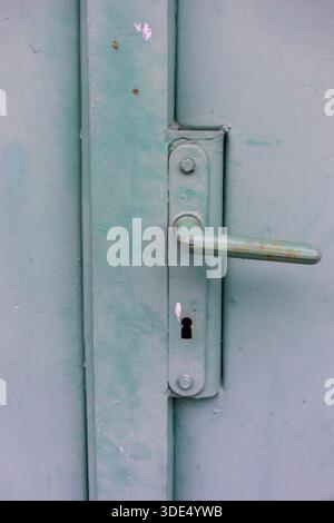 Weathered green metal door handle and keyhole with worn paint and industrial texture Stock Photo
