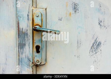 Distressed metal door handle with peeling paint and rust, capturing industrial decay and texture Stock Photo