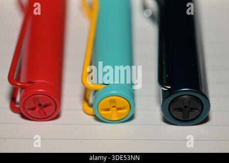 Close-up of three colorful pens with unique end designs on lined paper. Stock Photo