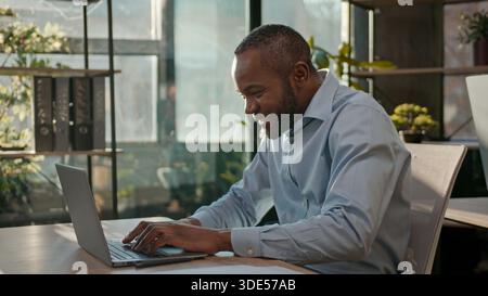 African American 40s business man typing laptop web service cyberspace adult businessman working online at office smiling mature male executive worker Stock Photo
