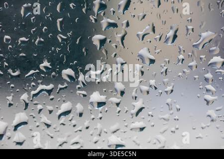 Close up view of water drops on glass creating an abstract background with soft reflections and blurred shapes. Minimal and modern texture representin Stock Photo