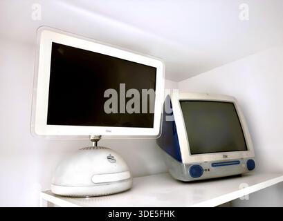Two vintage Apple iMac G3 and iMac G4 desktop computers on a white shelf in a minimalist interior setting Stock Photo