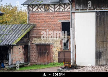 Abandoned traditional farm buildings with brick and half-timbered architecture in a rural countryside setting. Weathered agricultural buildings . Stock Photo