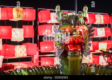 Illuminated dragon head lantern at night with blurred red lanterns, representing Lunar New Year prosperity and cultural heritage. Stock Photo