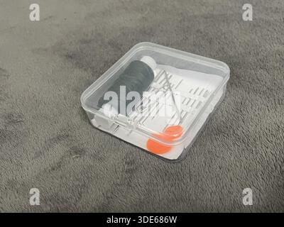 A tailor's sewing kit on a table. Needles, thread, and fabric for sewing. Stock Photo
