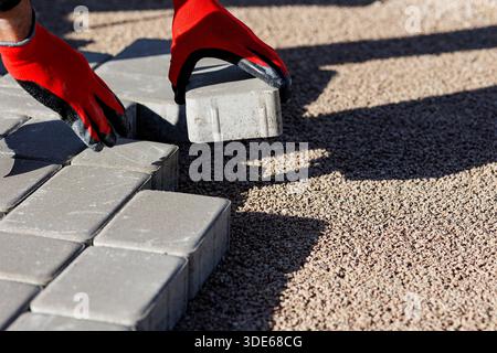 Worker laying concrete paving blocks for sidewalk construction Stock Photo