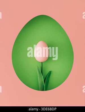 Spring composition with tulip made of pink Easter egg visible through an egg shaped gap on green background. Easter concept. Stock Photo