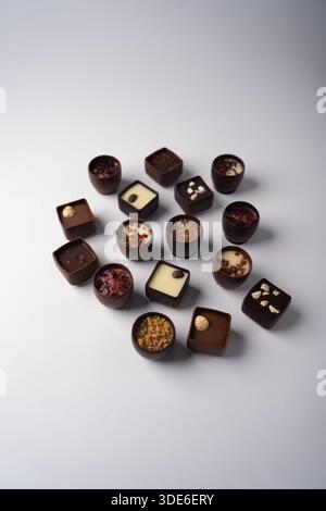 assorted gourmet filled chocolates arranged on a clean white surface under soft studio lighting, rich brown and cream tones, elegant minimalist presen Stock Photo