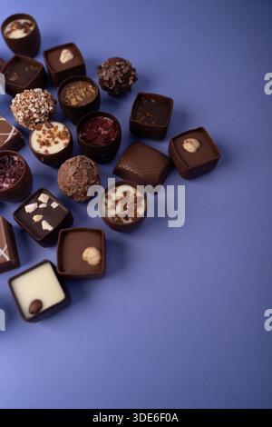 assorted artisanal chocolate bonbons and truffles arranged in a diagonal cluster on a smooth purple backdrop, showcasing glossy ganache, textured topp Stock Photo