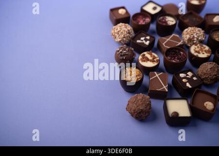assorted artisanal chocolate bonbons and truffles arranged on a lavender-purple tabletop flatlay, an elegant, decadent gourmet display showcasing vari Stock Photo