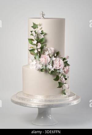 Elegant two-tier wedding cake with an extra-tall top tier, decorated with handcrafted sugar paste pink roses, white jasmine flowers, and green leaves Stock Photo