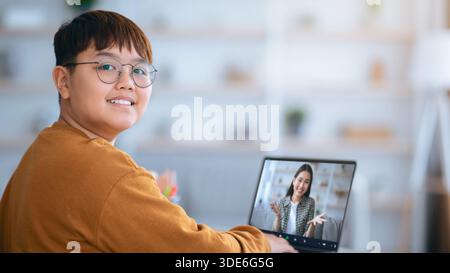 Young Person Interacts With a Woman on a Video Call While Sitting at a Desk in a Bright Room Stock Photo