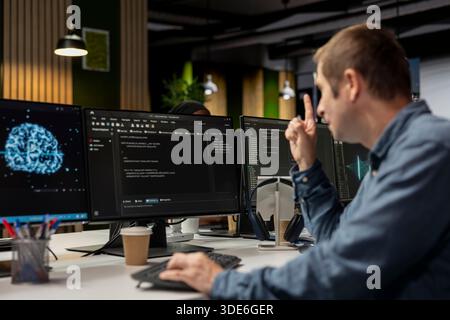 System administrator using computer in tech startup office to develop programs using AI automation. IT expert working on PC, debugging applications with artificial intelligence deep learning Stock Photo