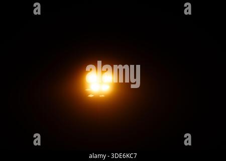 Four bright yellow LED lights radiating warm glow in a dark, mysterious setting Stock Photo