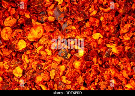 Red chili flakes creating a hot, textured background Stock Photo