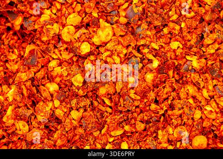 Crushed red pepper flakes creating a vibrant fiery texture background Stock Photo