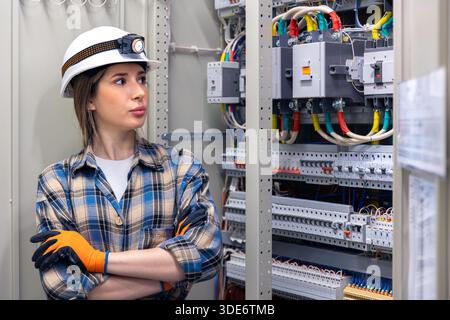 Female engineer inspecting electrical cabinet in control room. Panel inspection. Stock Photo