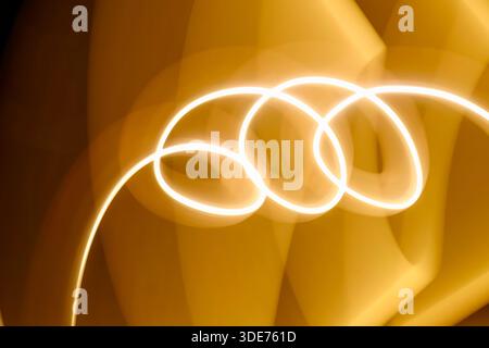 Abstract image featuring flowing light trails, creating curved lines with a warm, glowing tone. The light paints an organic, dynamic texture against a Stock Photo